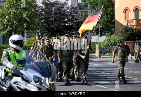 Potsdam, Deutschland. 08 Aug, 2019. Soldaten der Bundeswehr tragen eine deutsche Flagge und März durch eine Straße in Potsdam. Quelle: Britta Pedersen/dpa-Zentralbild/dpa/Alamy leben Nachrichten Stockfoto