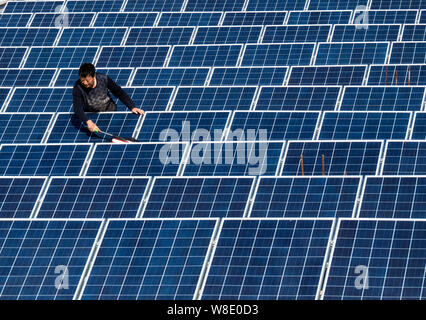---- Ein chinesischer Arbeiter Stäube aus Sonnenkollektoren auf dem Dach Photovoltaik- Kraftwerk in Baokang Maqiao Stadt, Grafschaft, Xiangyang City, Central China" Stockfoto