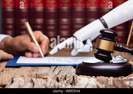 Roboterhand Unterstützung der Person, die für die Unterzeichnung dieses Dokuments reflektierende Schreibtisch Im Gerichtssaal Stockfoto
