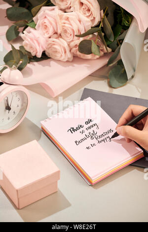 Hände Frau mit Stift, bereit zu schreiben. Rosa Rose, Pen und Geschenk mit rosa Herz auf weißem Tabelle. Liebe Konzept. Valentinstag Konzept. Die Mutter! Stockfoto