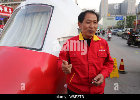 Pensionierte chinesischen Ingenieur Yuan Jingying interviewt wird neben seinem hausgemachten Hubschrauber-förmige Fahrzeug auf einer Straße in Zhengzhou City, Central China Hena Stockfoto