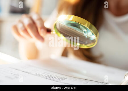 Unternehmer Analyse Bill durch Lupe im Büro Stockfoto