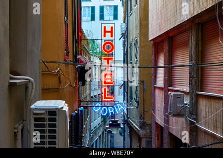 Genua (Genova), Italien - 30. Juni 2019: Roter Neon Hotel Zeichen an der Wand, in der engen Straße in Genua Stockfoto