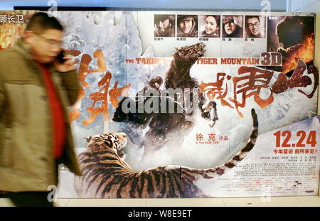 ---- Eine Chinesische filmgoer Spaziergänge hinter einem Plakat des Films "der Tiger Mountain" in einem Kino in Kunshan City, Central China Provinz Hubei Stockfoto