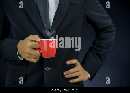 Mann in Anzug mit roten Tasse Kaffee auf schwarzem Hintergrund Stockfoto