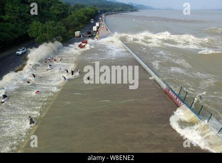 Besucher und Anwohner wie Wellen aus einem Tidal Bore Schwankung hinter einer Barriere am Ufer des Qiantang Fluss in Hangzhou City, East China Zhejian Stockfoto