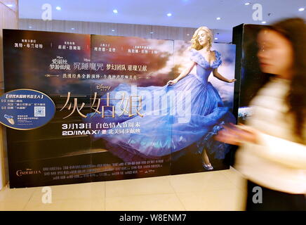 ---- Eine Chinesische filmgoer Spaziergänge hinter einem Plakat des Films "Aschenputtel" in einem Kino in Kunshan City, Central China Provinz Hubei, 9. März 2015. Stockfoto