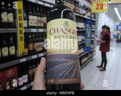 ---- Ein Kunde Geschäfte für eine Flasche Changyu trockener Rotwein in einem Supermarkt in Nantong Stadt, im Osten der chinesischen Provinz Jiangsu, 1. November 2014. Yant Stockfoto