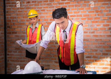 Frau und Mann arbeiten mit alten Mauer Hintergrund auf der Baustelle, Engineering Konzept Stockfoto