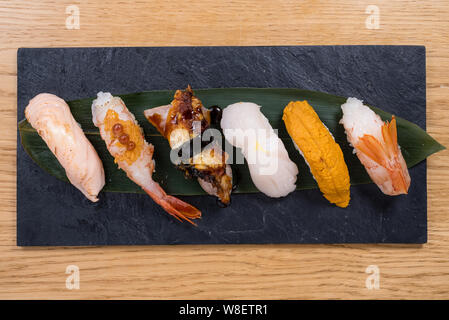 Verschiedene Sorten von Nigiri, Pacific Seeigel, gedünsteter Lachs, gedämpfte Garnelen, Kaviar, gebratener Aal und Squid auf einer Schiefertafel Platte Stockfoto