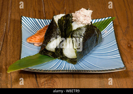 Onigiri gebratener Thunfisch und Lachs, in Seetang eingewickelt, darl Holz Tisch Hintergrund Stockfoto