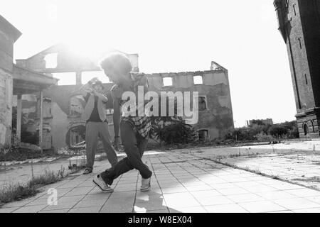 Junge männliche African American hip hop oder Street Dancer mit lockiges Afro-Haar seidig seine energische dance Routine in einer Stadt mit der Sonne backlig Stockfoto