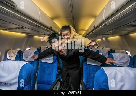 Ein Mitarbeiter von China Eastern Airlines wirft mit der vier Jahre alten Beinlose junge Xiao Feng auf seinem Rücken an Bord ein Passagier Jet an der Wuhan Tianhe Intern Stockfoto