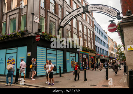 Käufer und Touristen zu Fuß entlang der Carnaby Street in London. Stockfoto