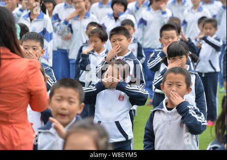 Junge chinesische Studenten lernen Handzeichen für die Alarmierung Raucher an einer Schule in Peking, China, 11. Mai 2015. Studenten in Peking starten Stockfoto