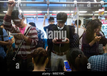 ---- Passagiere nutzen ihre Smartphones in einer U-Bahn in Shanghai, China, 19. Mai 2015. China hat rund 1,3 Milliarden Handynutzer am Ende Stockfoto