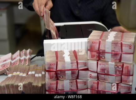 ---- Eine chinesische Angestellte verwendet eine Cash - Zählmaschine RMB (Renminbi) Yuan Banknoten bei einer Bank in der Stadt Qionghai zu zählen, South China Hainan Provinz, Stockfoto