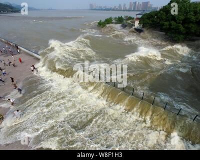 Besucher und Anwohner wie Wellen aus einem Tidal Bore Schwankung hinter einer Barriere am Ufer des Qiantang Fluss in Hangzhou City, East China Zhejian Stockfoto