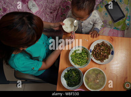 Zhang Wei füttert ihr 3-jähriger Sohn Tutu, der leidet an Leukämie, an der Wohnung, die Sie in Hanshou county vermietet, Stadt Changde, zentrale Chinas Stockfoto