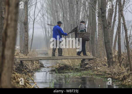 Armlose Chinese Jia Wenqi, rechts, führt seinen blinden Freund Jia Haixia mit einem Ärmel seines Mantels an einem Kanal, der über eine Brücke auf dem Weg kreuz Stockfoto