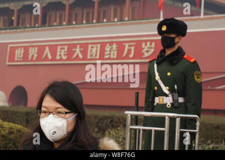 Ein Tourist das Tragen einer Maske an einem maskierten paramilitärischen Polizisten Wache vor dem himmlischen Podium in schweren Smog in Peking, Ch Stockfoto