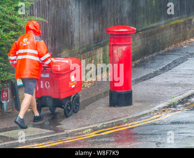 Bournemouth, Dorset, Großbritannien. August 2019. Wetter in Großbritannien: Das schlechte Wetter ist gekommen, da sintflutartige Regenfälle in Bournemouth fallen. Postbote in Shorts eilt auf seine Runden, unabhängig vom Wetter! Quelle: Carolyn Jenkins/Alamy Live News Stockfoto