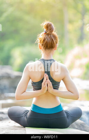 Asiatische junge Frau Yoga in der Nähe von Wasserfall Stockfoto