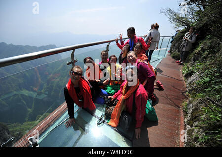 Touristen posieren für Fotos auf dem Glas Skywalk auf der Klippe von Tianmen Mountain (oder Tianmenshan Berg) in Zhangjiajie National Forest Park in Zhangj Stockfoto