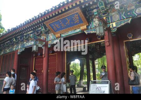 ---- Fußgänger für Fotos vor einem Tor der Peking Universität in Peking, China, 17. August 2013 darstellen. Akademische Leistung in wichtigen Themen Stockfoto