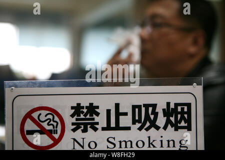 --FILE - Ein chinesischer Mann raucht eine Zigarette in der Nähe eines no-smoking sign in Ningbo City, der ostchinesischen Provinz Jiangsu, 25. November 2014. China ist einer der Th Stockfoto