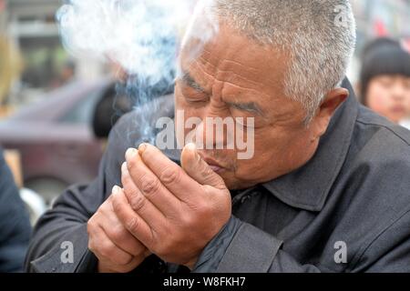 --FILE - Ein chinesischer Mann raucht auf einer Straße in Chiping County, Liaocheng City, der ostchinesischen Provinz Shandong, 10. Mai 2015. Rauchen tötet Stockfoto