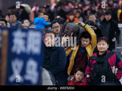 Ein chinesischer Mann trägt sein Gepäck, wie er und andere Passagiere, die Rückkehr aus dem Chinesischen Neujahrsfest oder Spring Festival zu arbeiten die Hangzhou verlassen Stockfoto