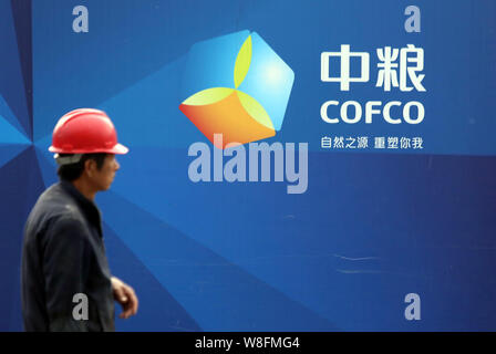 ---- Ein chinesischer Wanderarbeiter Wanderungen vorbei an einer Tafel von COFCO (China National Getreide, Öle und Lebensmittel Corporation) auf der Baustelle Stockfoto