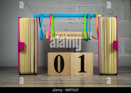 Bunte September noch leben mit Büchern, Gummibänder und rustikalen Zeichen für den Monat gegen eine weiße Wand Stockfoto