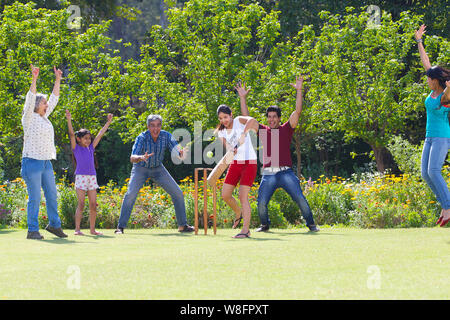 Familie spielen Cricket in Rasen Stockfoto