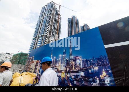 ------ Chinesische Wanderarbeiter Spaziergang, vorbei an einer Anschlagtafel zeigt eine Nachtansicht der Lujiazui Finanzviertel in Pudong auf der Baustelle eines Stockfoto