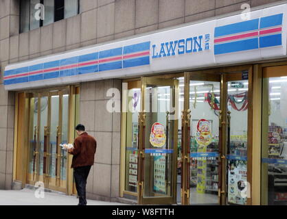 ---- Ein Fußgänger geht hinter einem Convenience Store von Lawson in Chongqing, China, 14. Dezember 2013. Es kann sich wie gibt es einen Convenience Store o Stockfoto