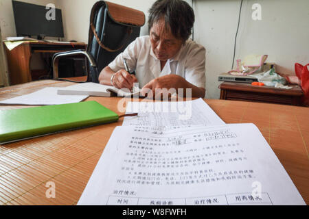 (190809) - NANCHANG, August 9, 2019 (Xinhua) - Gao Yinshui Bewertungen macht sich Notizen auf Aufzeichnung der Patienten in Lixin Dorf Meiling Stadt im Landkreis Wanli Nanchang Stadt, im Osten der chinesischen Provinz Jiangxi, Aug 8, 2019. Fast jeden Tag in den letzten vier Jahrzehnten hat sich die 69-jährige Dorf Arzt Gao Yinshui Spaziergänge für Meilen auf Bergstraßen, ihre Patienten in neun verschiedenen Dörfern zu sehen. Am Ende von 1970, des Gao Mutter hatte ein Notfall und hatte das Glück, von einem lokalen ländlichen Arzt gespeichert werden. Da von, dass Gao Yinshui gab die Gelegenheit zu einem Lehrer und wählte eine ländliche Arzt zu werden. Jedoch hat sie Stockfoto