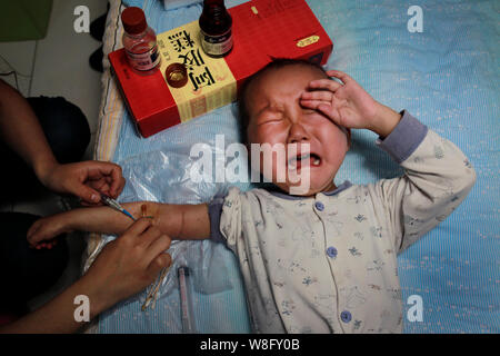 Zhang Wei spritzt ihr 3-jähriger Sohn Tutu, der leidet an Leukämie, mit Medizin an der Wohnung, die Sie in Hanshou county vermietet, Stadt Changde, Stockfoto