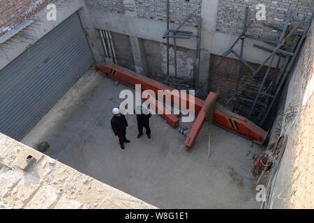 Chinesischen Strafverfolgungsbehörden prüfen die Verfüllung eines 3-level und 700 m² großen Keller illegal von Haus in Shaluo Hütte gebaut Stockfoto