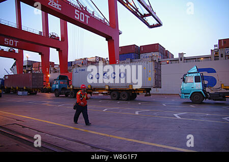 ---- Ein chinesischer Arbeiter Spaziergänge hinter einem Lkw mit einem Container der COSCO auf einem Kai am Hafen in Rizhao Rizhao Stadt geladen, der Osten China Shandong pro Stockfoto
