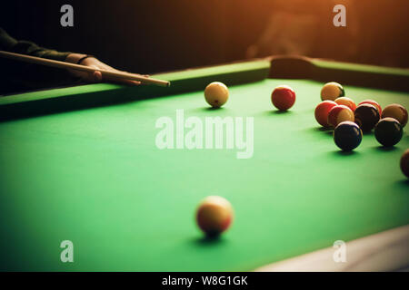 Der Spieler hilft sich selbst mit seiner Hand die Cue am Billard Kugel liegen unter anderem auf den grünen Billardtisch zu Ziel Stockfoto