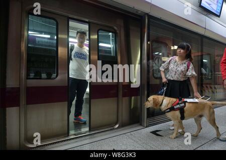 Blindenhund Zi lange Wartezeiten für eine U-Bahn mit seinem Besitzer Wu Wenhao an der U-Bahnstation in Peking, China, 1. Mai 2015. Beijing am Freitag (1. Mai 2015) Stockfoto