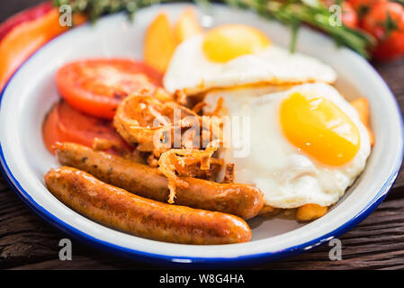 Typial Frühstück mit Eiern, Tomaten, Zwiebeln und Wurst auf dem Teller Stockfoto