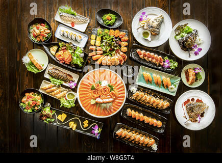 Satz von Lachs Sushi, Maki und Brötchen, Grill saba Fisch am Schwarzen rustikalen, mit Holz. Stockfoto