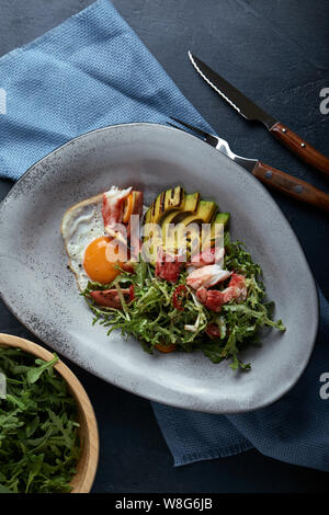 Salat mit Krabben und Avocado auf einem dunklen Hintergrund. Rucola Salat, gewürzt mit Soße auf Weißwein mit Krabben Fleisch und gegrilltem Avocado in Weichen Stockfoto