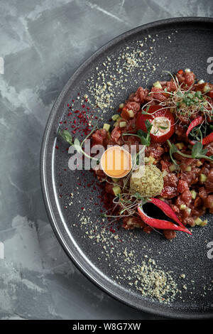 Beef Tartar mit Eigelb auf einem grauen Oberfläche, Ansicht von oben, close-up. Stockfoto