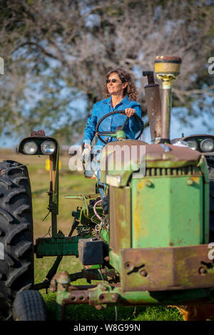 Eine Frau Bauer sitzt auf 1964 John Deere 2510 Traktor ihrer Familie an einem sonnigen Herbsttag Stockfoto