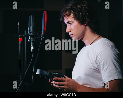 Jungen gutaussehenden Sänger Mann legt auf Kopfhörer im Studio. Stockfoto