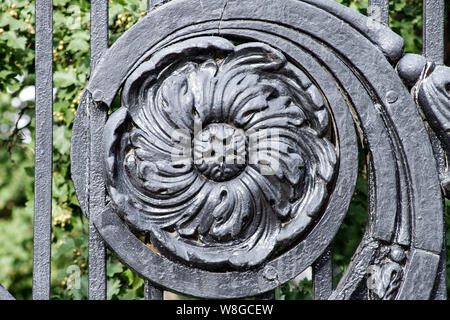 Antik schwarz Gusseisen verzierte Gitter mit staubigen Oberfläche floralen Elementen. Alte Tür Gitter. Die Details der retro Sign-in Moskau, Russland Stockfoto